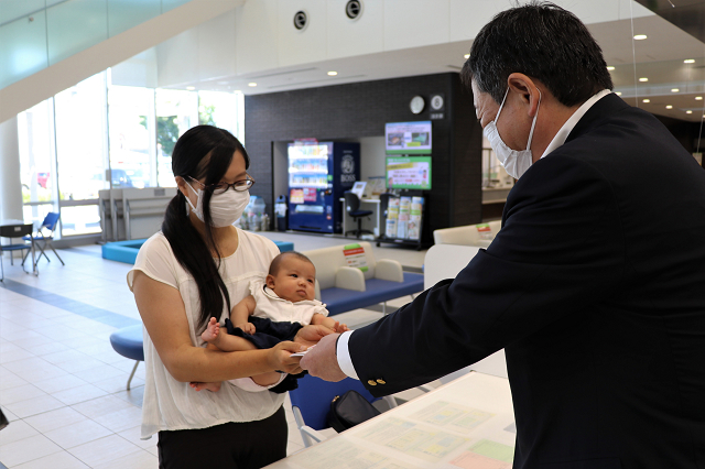 窓口で市長が子育て家族応援チケットを渡す