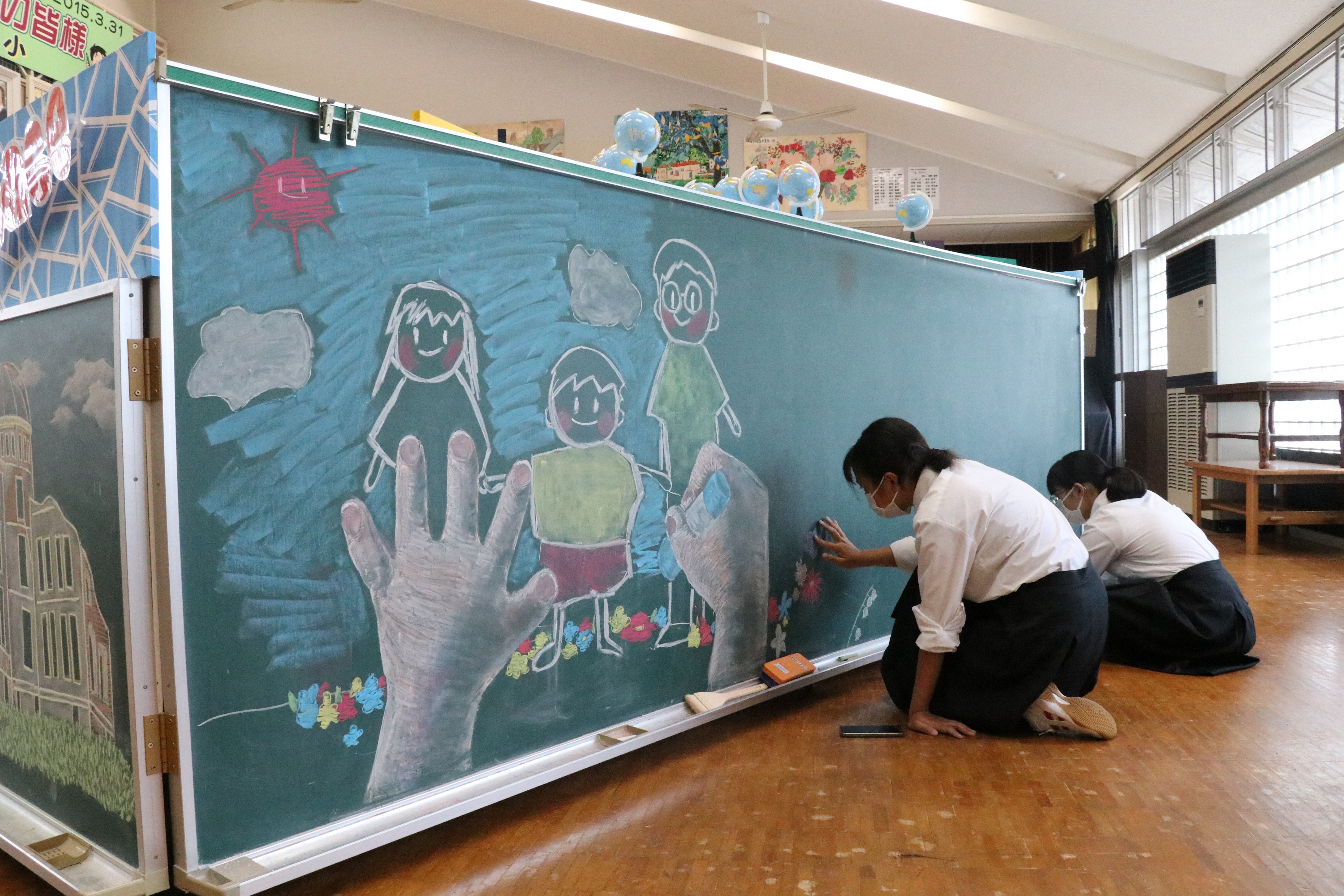 美術部の生徒2人が黒板に描いている様子