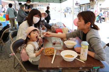 お母さんに焼きそばを食べさせてもらう女の子