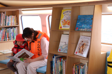 図書館船内で一緒に本を読むお母さんと子ども