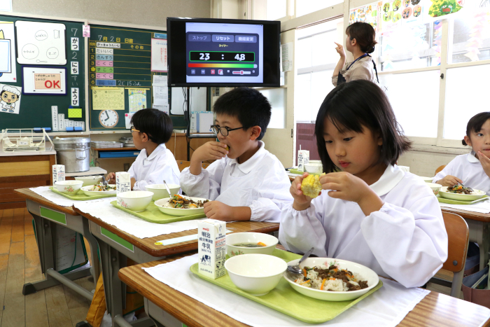 とうもろこしを食べる児童