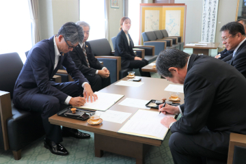 協定書に署名する佐伯市長と近藤憲司支社長