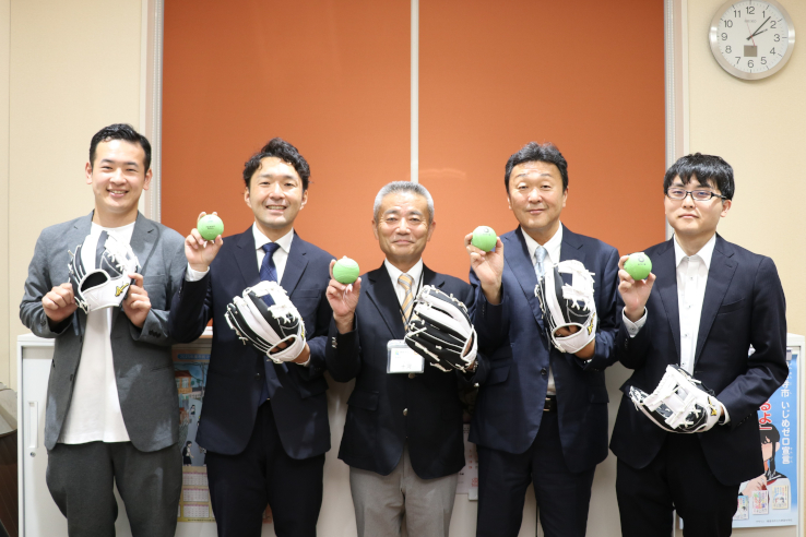 寄贈された野球用具を持って集合写真