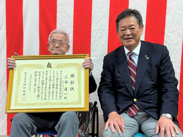 顕彰状を持つ三谷さんと佐伯市長