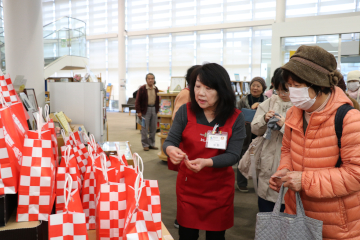 スタッフの説明を聞きながら福引きをする人