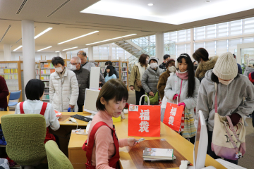 福袋を手に、貸し出し手続きを待つ人々