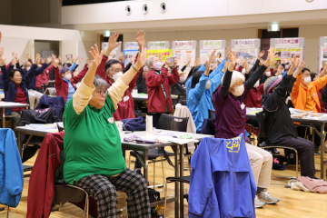 手本を見ながら、介護予防体操に取り組む人々