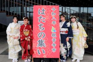 「はたちの集い」の看板と一緒に記念撮影をする振り袖の女性4人